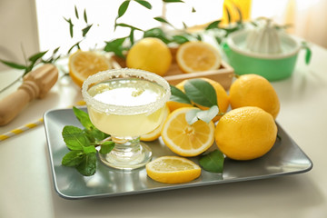 Platter with glass of juice and lemons on white table
