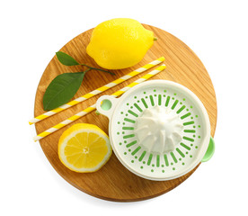 Wooden board with squeezer, lemons and straws on white background
