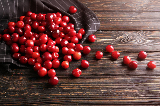 Napkin with heap of cherries on wooden background