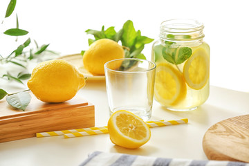 Jar with lemonade, glass and lemons on light table