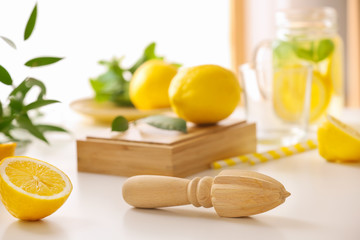 Wooden juicer and half of lemon on light table