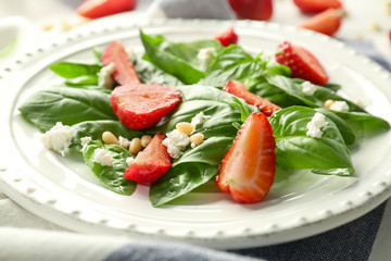 Tasty salad with spinach and strawberry on plate, close up