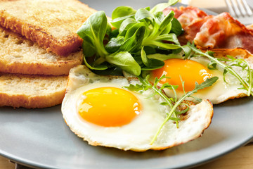 Tasty breakfast with fried eggs on plate, closeup