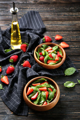 Bowls with tasty strawberry spinach salad on table
