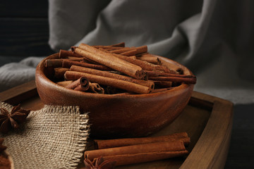 Bowl with cinnamon sticks on wooden tray