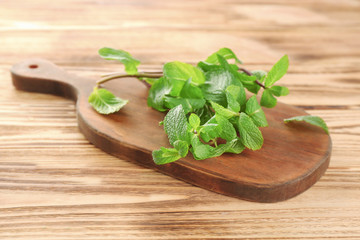 Wooden board with lemon balm on table