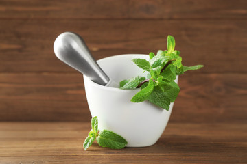 Mortar with lemon balm on wooden table