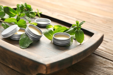 Containers with lemon balm salve and leaves on table - obrazy, fototapety, plakaty