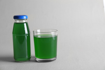 Bottle and glass with delicious juice on light background