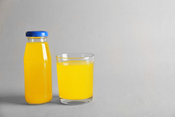 Bottle and glass with delicious juice on light background
