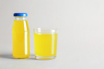 Bottle and glass with delicious juice on light background