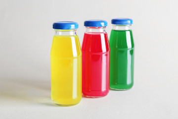 Different delicious juices in bottles on light background