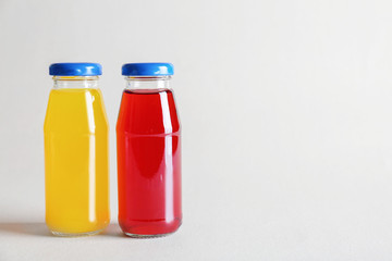 Different delicious juices in bottles on light background