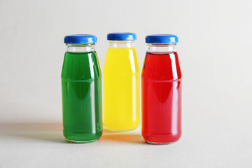 Different delicious juices in bottles on light background