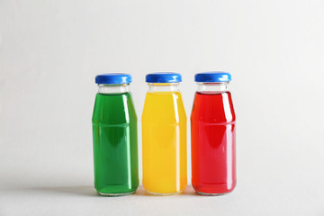 Different delicious juices in bottles on light background