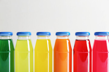 Different delicious juices in bottles on light background