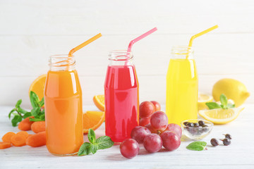 Delicious juices in bottles and fruits on wooden table