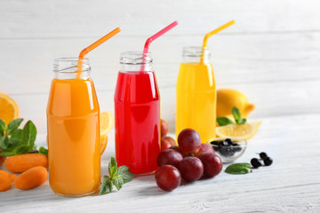 Delicious juices in bottles and fruits on wooden table