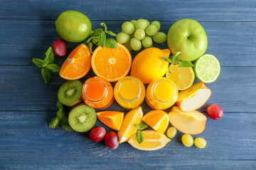 Delicious juices in bottles and fruits on wooden background