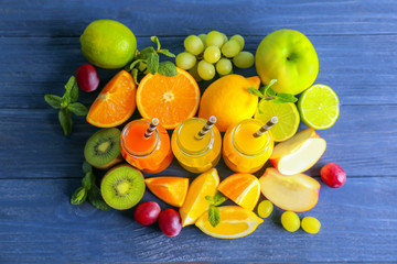Delicious juices in bottles and fruits on wooden background