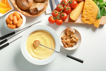 Cheese fondue in plate and different products on white table