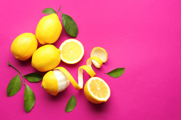 Delicious sliced and peeled lemons with green leaves on color background