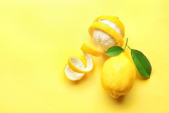 Fresh lemons and green leaves on color background