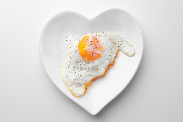 Plate with over hard fried egg on light background