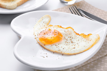 Cutlery and plate with over hard fried egg on light table