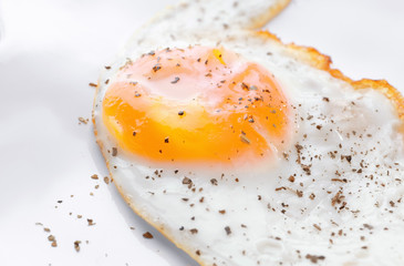 Closeup view of over hard fried egg on white plate