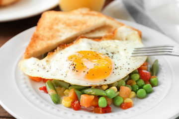 Plate with delicious over hard fried egg, toasts and vegetables, closeup