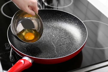 Woman pouring egg from bowl into frying pan