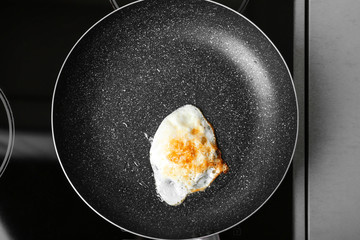 Frying pan with over hard fried egg on stove, top view