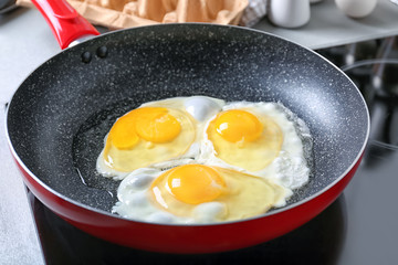 Frying pan with delicious eggs on black stove