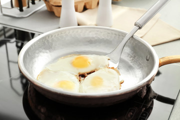 Frying pan with eggs and spatula on stove
