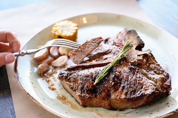 Slice of beefsteak on fork over plate