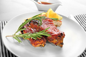Plate with delicious pork ribs on table, closeup