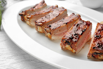 Plate with delicious pork ribs on wooden table, closeup