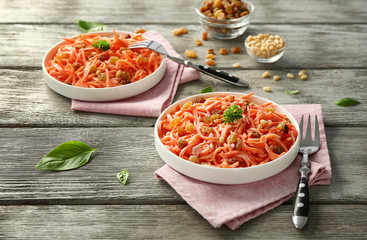 Plates with delicious carrot raisin salad on wooden table