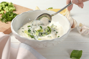 Young woman preparing delicious sauce on wooden table