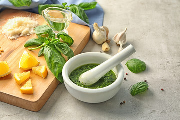 Delicious sauce in mortar with pestle and ingredients on grey background