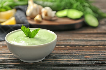 Delicious yogurt sauce in bowl on wooden background