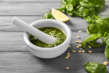 Delicious sauce in mortar with pestle and ingredients on wooden background