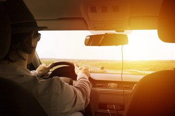 video recorder driving a car on highway. The hidden camera is hidden in the rear-view mirrorThe man in the hat drives the car. Sunset filter effect. Safety on the road. The road to success
