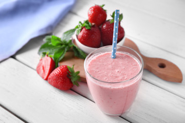 Glass of delicious strawberry homemade smoothie on wooden background