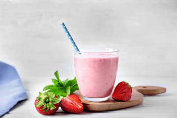 Glass of delicious strawberry homemade smoothie on light background