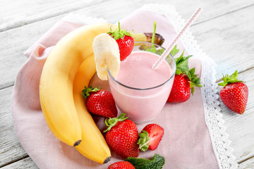 Glass of delicious strawberry and banana homemade smoothie on wooden background