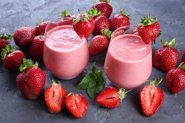 Delicious strawberry homemade smoothie in glasses on grey background