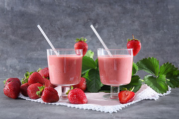 Delicious strawberry homemade smoothie in glasses on grey background