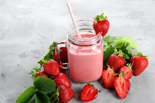 Delicious strawberry homemade smoothie in mason jar on grey background